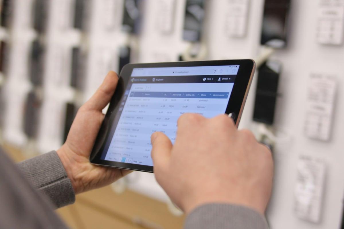 Checking stock records on a tablet in front of warehouse shelving